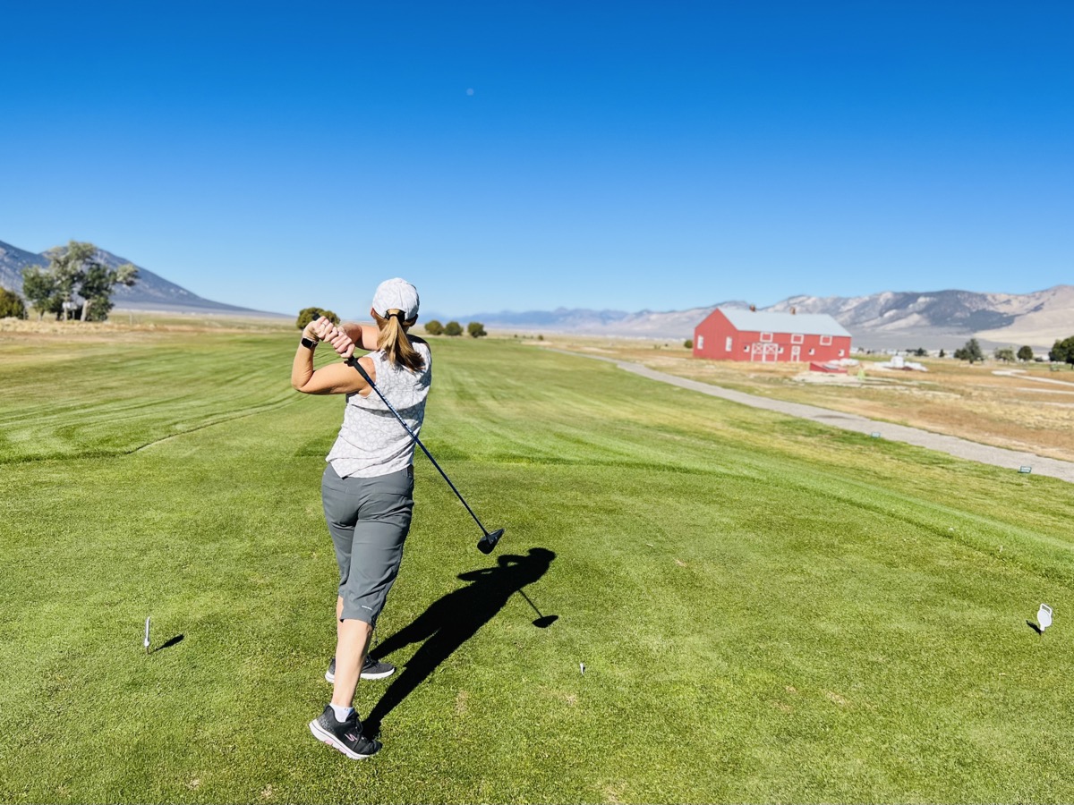 Julie tees off near the red barn